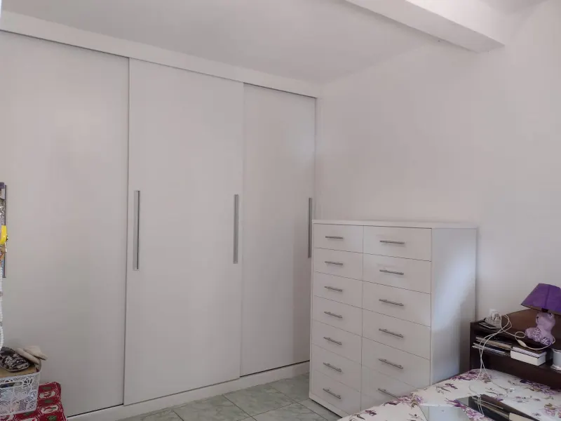 Quarto com guarda-roupa embutido de portas de correr brancas e cômoda de 14 gavetas sob medida