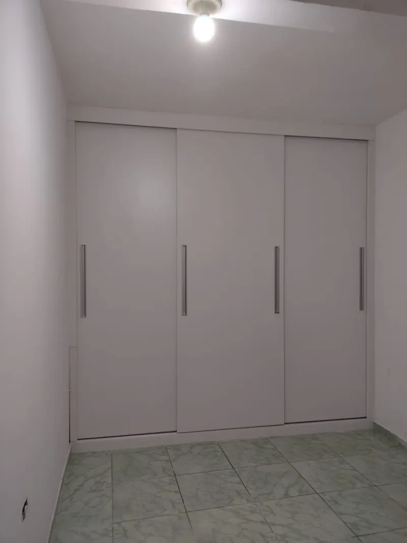 Guarda-roupa embutido branco de parede a parede com quatro portas de correr e puxadores verticais