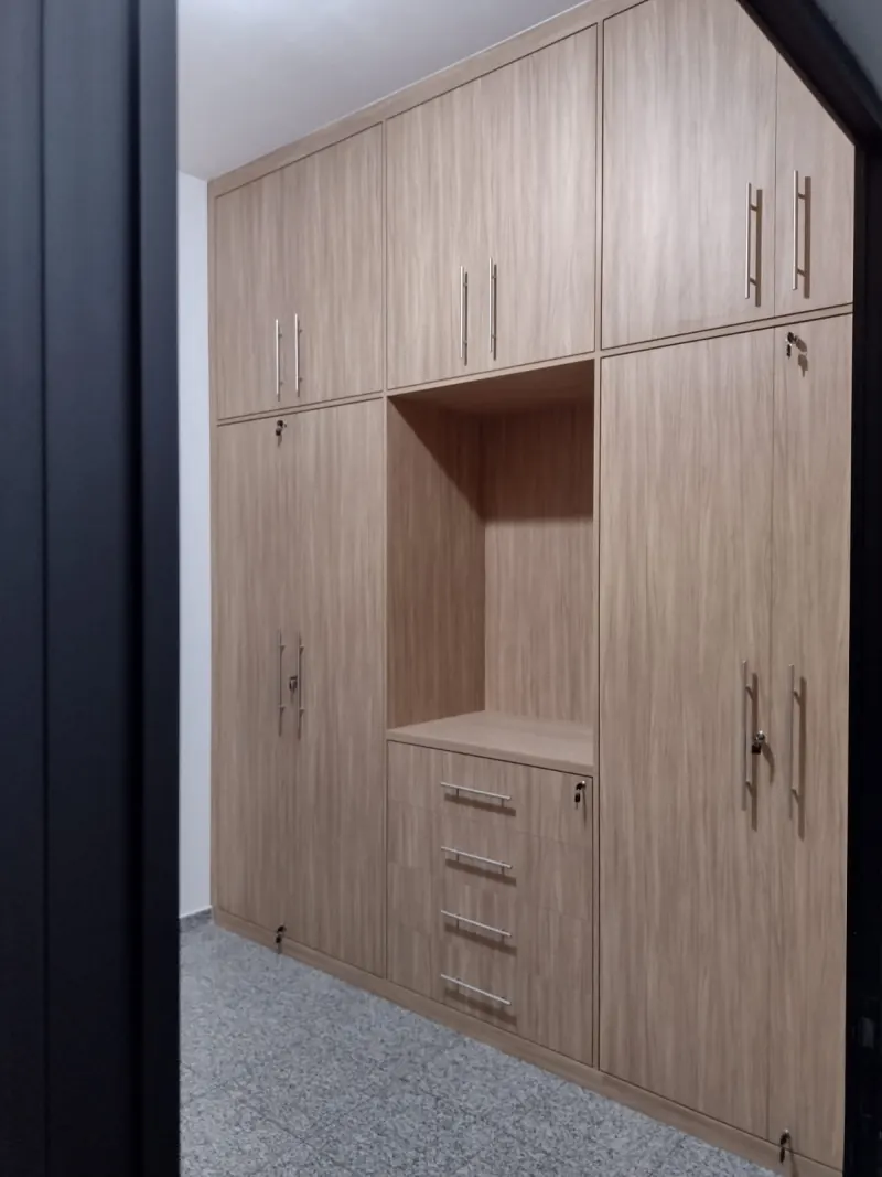 Guarda-roupa planejado em MDF amadeirado com seis portas, nicho central para TV, gaveteiro e fechaduras
